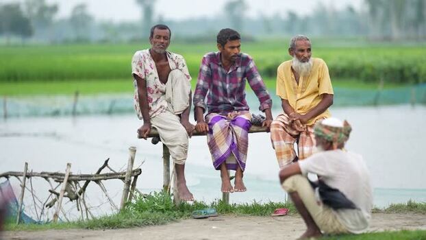 View of men sitting on a wooden bench in Bogura Bangladesh.