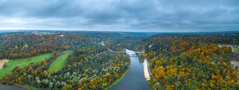 Aerial view of the Gauja River winding through the vibrant autumn forests of the Sigulda valley under a cloudy sky in Sigulda Sigulda Municipality Latvia. Aerial view of the Gauja River winding through the vibrant autumn forests of the Sigulda valley under a cloudy sky in Sigulda Sigulda Municipality Latvia.