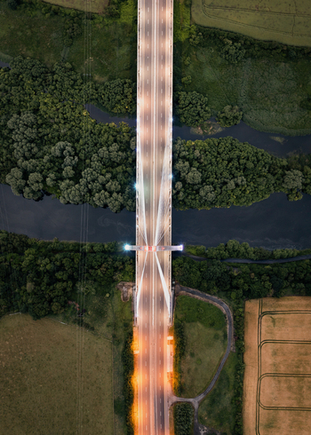 Aerial view of Mary McAleese Boyne Valley Bridge illuminated at dusk over the River Boyne and lush green forests in Drogheda County Louth Ireland. Aerial view of Mary McAleese Boyne Valley Bridge illuminated at dusk over the River Boyne and lush green forests in Drogheda County Louth Ireland.