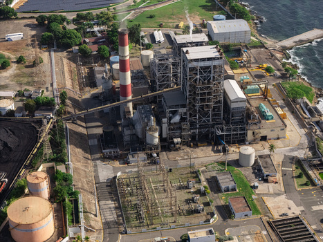 Aerial view of an industrial power plant with a tall red and white chimney storage tanks and electrical infrastructure in Bajos de Haina San Cristobal Provinc Dominican Republic.