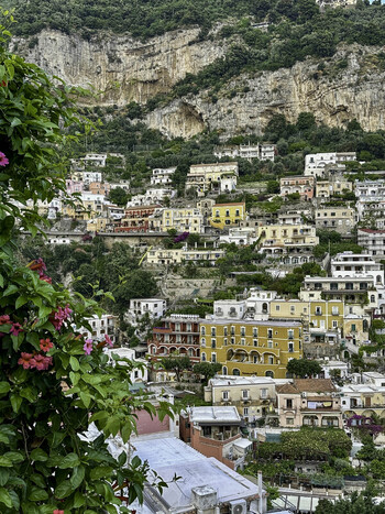 View of Positano with its iconic pastel colored buildings clinging to the steep hillside lush green foliage and vibrant flowers in the foreground Amalfi Coast Italy. View of Positano with its iconic pastel colored buildings clinging to the steep hillside lush green foliage and vibrant flowers in the foreground Amalfi Coast Italy.