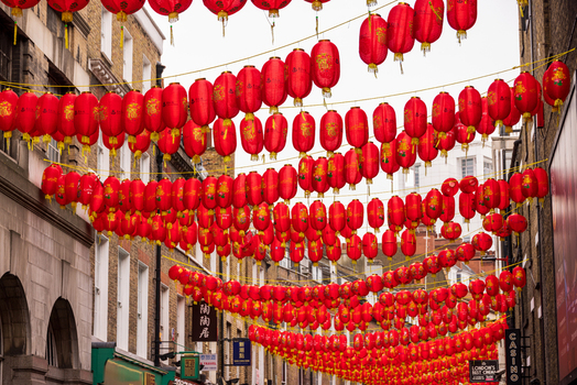 London United Kingdom 12 May 2025 View of traditional red Chinese lanterns hanging across the streets of Chinatown between historic brick buildings under an overcast sky.