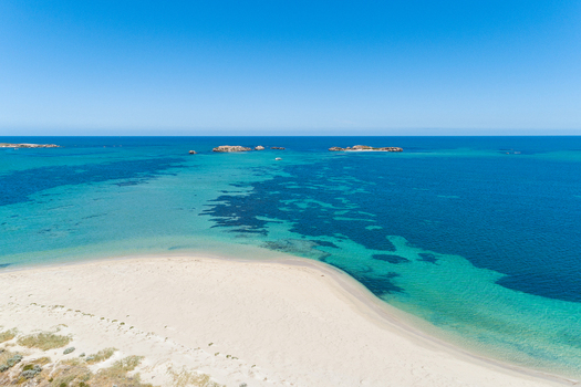Aerial view of the pristine white sand beach meeting turquoise waters with offshore islands under a clear blue sky in Perth Western Australia Australia. Aerial view of the pristine white sand beach meeting turquoise waters with offshore islands under a clear blue sky in Perth Western Australia Australia.