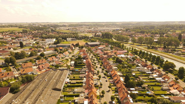 Aerial view of residential houses with red tiled roofs tree lined streets and a nearby canal in the town of Saint Omer Hauts de France France. Aerial view of residential houses with red tiled roofs tree lined streets and a nearby canal in the town of Saint Omer Hauts de France France.