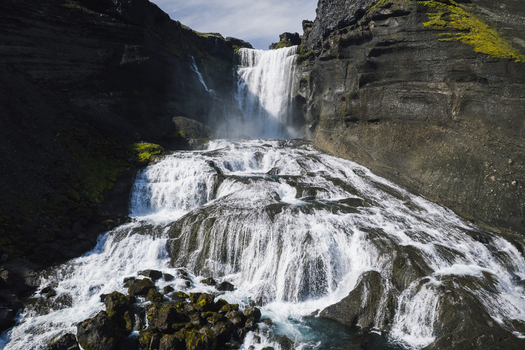Aerial view of cascading waters of Ofaerufoss waterfall plunge down rugged cliffs creating a dynamic interplay of light and shadow Highlands of Iceland. Aerial view of cascading waters of Ofaerufoss waterfall plunge down rugged cliffs creating a dynamic interplay of light and shadow Highlands of Iceland.