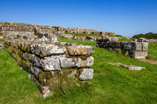 View of the ancient stone walls and archaeological remains of Vindolanda Roman fort under a clear blue sky in Hexham England United Kingdom. View of the ancient stone walls and archaeological remains of Vindolanda Roman fort under a clear blue sky in Hexham England United Kingdom.