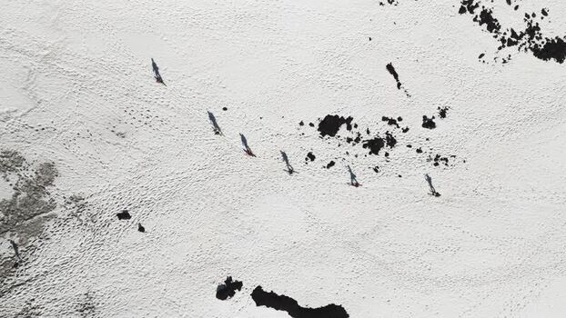 Aerial view of people walking on snowy volcanic slopes in Italy. Aerial view of people walking on snowy volcanic slopes in Italy.