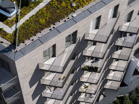 Aerial view of a modern apartment building with a green roof brick facade and geometric shadows cast by balconies in Krakow Lesser Poland Voivode Poland.