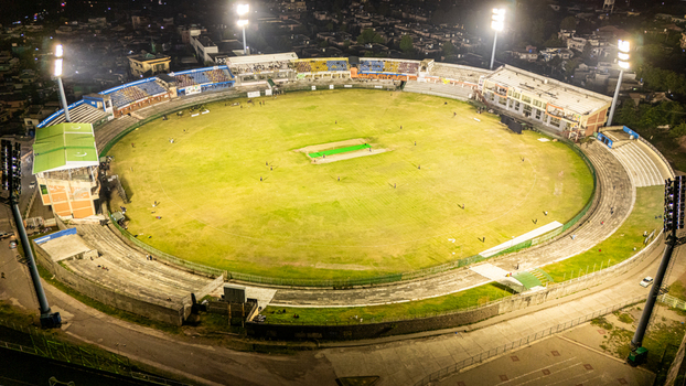 Aerial view of Muzaffarabad Cricket Stadium illuminated by bright floodlights at night with the surrounding urban landscape in Muzaffarabad Azad Kashmir Pakistan. Aerial view of Muzaffarabad Cricket Stadium illuminated by bright floodlights at night with the surrounding urban landscape in Muzaffarabad Azad Kashmir Pakistan.