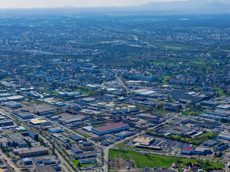 Aerial view of a sprawling cityscape where industrial buildings meet residential areas a tapestry of rooftops under a soft sky Sausheim Grand Est France.