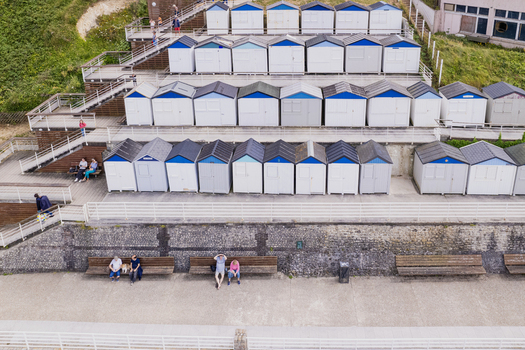 Veules les Roses France 18 June 2025 Aerial view of the iconic colorful beach huts arranged in rows along the promenade with people relaxing on benches. Veules les Roses France 18 June 2025 Aerial view of the iconic colorful beach huts arranged in rows along the promenade with people relaxing on benches.