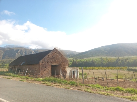 View of a rustic brick barn situated in the rural landscape of the Klein Karoo with mountains in the background and fields in the foreground in Robertson Western Cape South Africa. View of a rustic brick barn situated in the rural landscape of the Klein Karoo with mountains in the background and fields in the foreground in Robertson Western Cape South Africa.