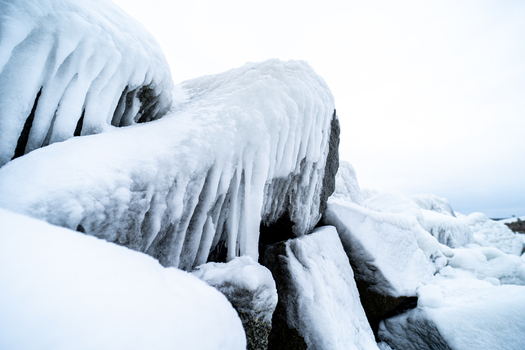 View of ice covered rocks near the Molenfeuer Sassnitz featuring thick layers of frozen sea spray and icicles on the coastal breakwater in Sassnitz Mecklenburg Vorpommern Germany.