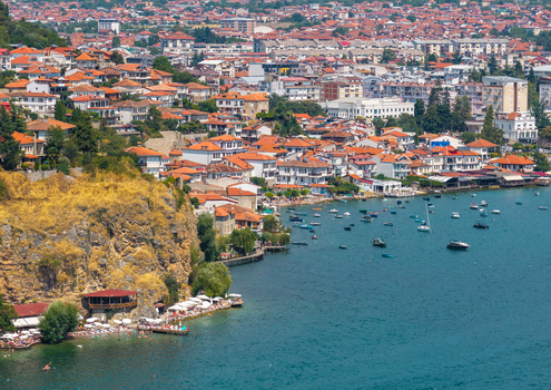 Aerial view of the historic town of Ohrid with red tiled rooftops rocky cliffs and boats on the clear blue waters of Lake Ohrid Ohrid Municipality of Ohrid North Macedonia.