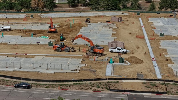 Aerial view of a construction site with heavy machinery including excavators and a loader working on concrete foundations for new buildings in Centennial Colorado United States.