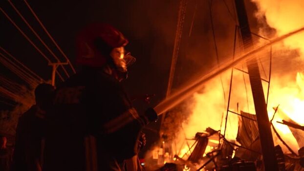 View of a firefighter spraying water on a large fire Bangladesh. View of a firefighter spraying water on a large fire Bangladesh.