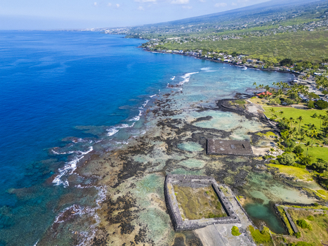 Aerial view of Kahalu u Beach Park featuring ancient stone heiau structures along the volcanic coastline and turquoise coral reefs in Kailua Kona Hawaii United States. Aerial view of Kahalu u Beach Park featuring ancient stone heiau structures along the volcanic coastline and turquoise coral reefs in Kailua Kona Hawaii United States.