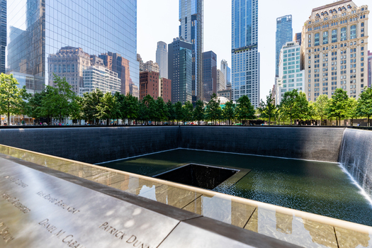 View of the 911 Memorial reflecting pool surrounded by lush green trees and modern skyscrapers in the financial district of New York New York United States. View of the 911 Memorial reflecting pool surrounded by lush green trees and modern skyscrapers in the financial district of New York New York United States.