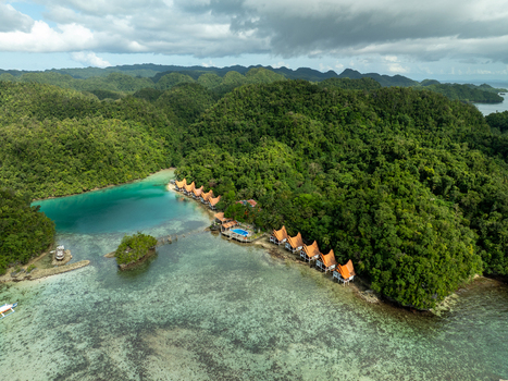 Aerial view of Bucas Grande resort with thatched roof villas nestled along a turquoise lagoon surrounded by lush green hills in Siargao Philippines. Aerial view of Bucas Grande resort with thatched roof villas nestled along a turquoise lagoon surrounded by lush green hills in Siargao Philippines.
