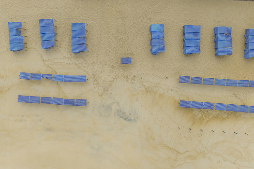 Aerial view of Praia de Sao Pedro de Moel with blue and white striped beach tents arranged in rows on the golden sand in Marinha Grande Leiria Portugal. Aerial view of Praia de Sao Pedro de Moel with blue and white striped beach tents arranged in rows on the golden sand in Marinha Grande Leiria Portugal.
