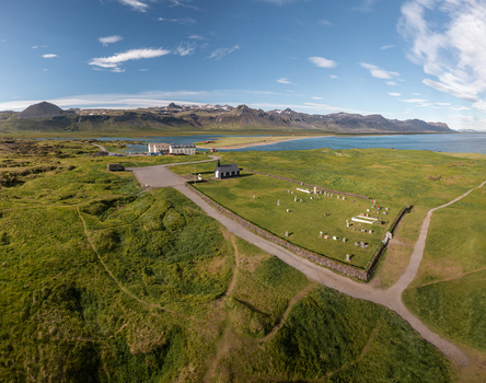 Aerial view of the iconic black wooden Budakirkja church and its historic cemetery surrounded by lush green fields and the rugged coastline of Budir Snaefellsbaer Iceland. Aerial view of the iconic black wooden Budakirkja church and its historic cemetery surrounded by lush green fields and the rugged coastline of Budir Snaefellsbaer Iceland.