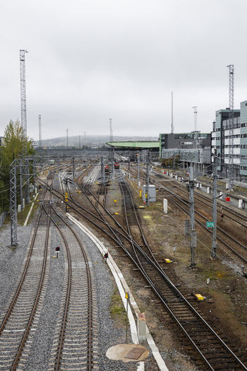 View of a railway yard with multiple tracks overhead power lines and modern buildings in the background under an overcast sky in Jyvaskyla Central Finland Finland.