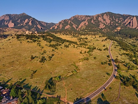 Aerial view of the NCAR and UCAR Foothills Laboratory nestled in the grassy foothills of the Flatirons with a winding road and mountain backdrop in Boulder Colorado United States.