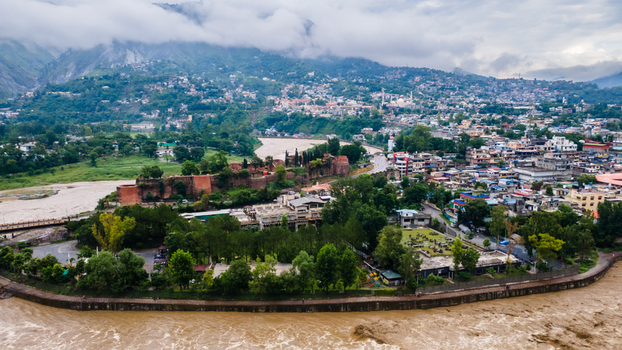Aerial view of the historic Red Fort surrounded by lush greenery and urban buildings along the winding river under a cloudy sky in Muzaffarabad Azad Kashmir Pakistan. Aerial view of the historic Red Fort surrounded by lush greenery and urban buildings along the winding river under a cloudy sky in Muzaffarabad Azad Kashmir Pakistan.