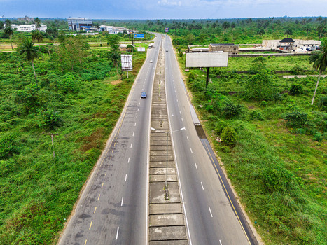 Aerial view of a multi lane highway stretching through lush tropical vegetation with billboards and distant buildings under an overcast sky in Port Harcourt Rivers Nigeria. Aerial view of a multi lane highway stretching through lush tropical vegetation with billboards and distant buildings under an overcast sky in Port Harcourt Rivers Nigeria.