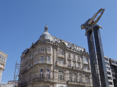 View of the El Sireno statue standing tall against a clear blue sky with a historic stone building in the background in Vigo Pontevedra Spain.