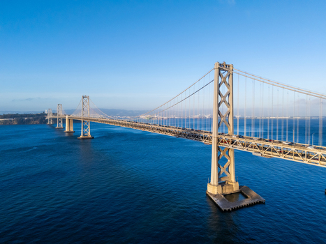 Aerial view of the San Francisco Oakland Bay Bridge spanning the deep blue waters of the bay with traffic flowing across the structure in San Francisco California United States. Aerial view of the San Francisco Oakland Bay Bridge spanning the deep blue waters of the bay with traffic flowing across the structure in San Francisco California United States.