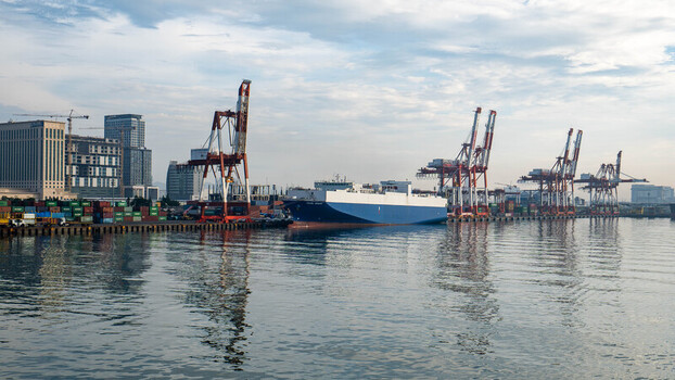 View of the Cebu Port Authority with a large cargo ship docked at the pier surrounded by shipping containers and industrial cranes in Cebu City Central Visayas Philippines. View of the Cebu Port Authority with a large cargo ship docked at the pier surrounded by shipping containers and industrial cranes in Cebu City Central Visayas Philippines.