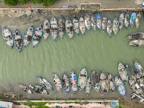 Aerial view of fishing boats docked in the harbor their colorful hulls reflecting in the murky water a tapestry of maritime life unfolds. Jepara Central Java Indonesia.
