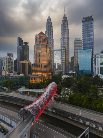 Kuala Lumpur Malaysia 11 March 2026 Aerial view of the illuminated Saloma Link bridge and Petronas Twin Towers against a cloudy twilight sky in the city center.