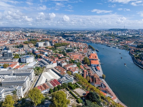 Aerial view of Porto showing the Douro River historic buildings rooftops and urban landscape under a blue sky in Porto Porto District Portugal.