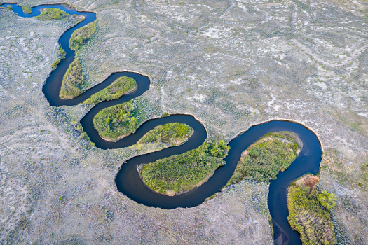 Aerial view of Owens River winding through the arid landscape with green vegetation along the banks in Inyo County California United States.