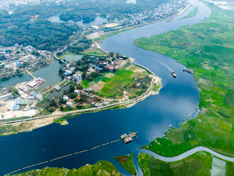 Aerial view of a winding river flowing through lush green agricultural fields and rural settlements near Dhaka Dhaka Division Bangladesh. Aerial view of a winding river flowing through lush green agricultural fields and rural settlements near Dhaka Dhaka Division Bangladesh.