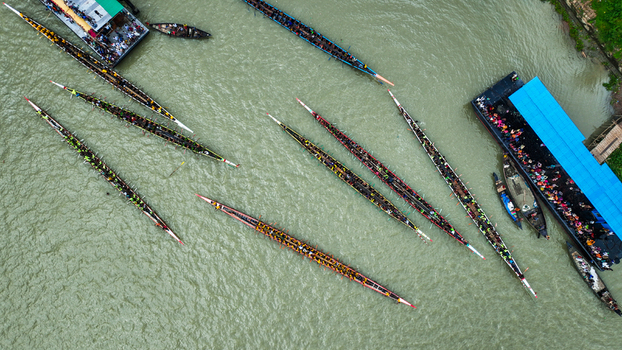 Baghabari Rajshahi Division Bangladesh 20 August 2022 Aerial view of a traditional boat race with long narrow boats filled with rowers and spectators on a large vessel.