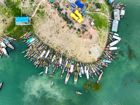 Rangamati Hill District Bangladesh 18 May 2024 Aerial view of Kaptai Lake with numerous traditional wooden boats moored along the shore colorful tarps and people gathered on the bank.