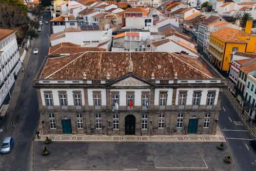 Aerial view of the historic Town Hall building with its neoclassical facade and tiled roof overlooking a paved square in Angra do Heroismo Azores Portugal.