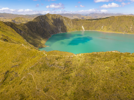 Aerial view of Quilotoa Lake with turquoise volcanic crater water surrounded by rugged mountain slopes and sparse vegetation under a bright blue sky Quilotoa Cotopaxi Ecuador. Aerial view of Quilotoa Lake with turquoise volcanic crater water surrounded by rugged mountain slopes and sparse vegetation under a bright blue sky Quilotoa Cotopaxi Ecuador.