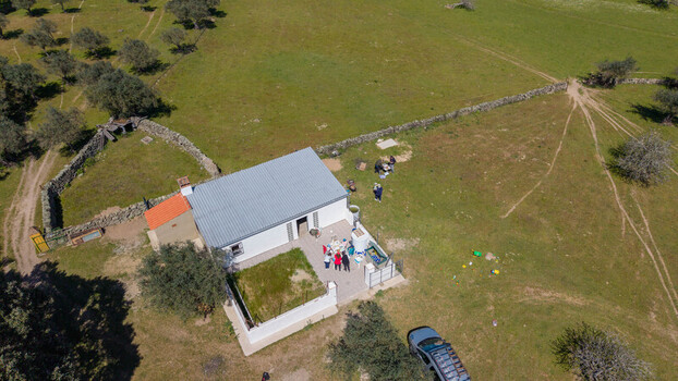 Aerial view of a building with a silver roof amidst green fields and scattered trees a blend of rural charm and modern simplicity Navas del Madrono Extremadura Spain.