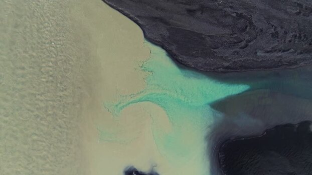 Aerial view of turquoise water mixing with black sand Iceland. Aerial view of turquoise water mixing with black sand Iceland.