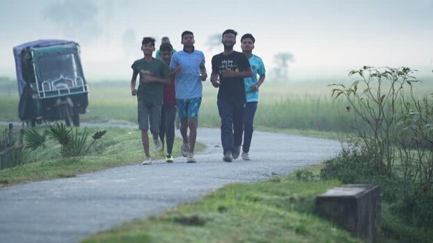 View of young men jogging on a rural road in Bogura Bangladesh.