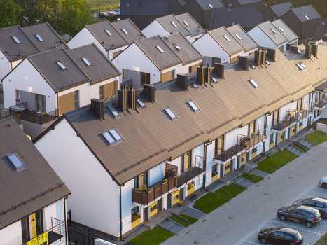 Aerial view of modern terraced houses with dark tiled roofs and skylights in a residential complex with a parking area in Wieliczka Lesser Poland Voivode Poland.