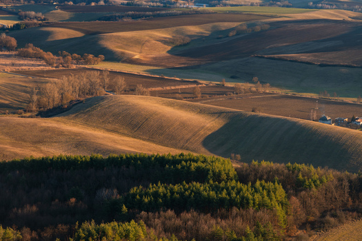 Aerial view of rolling golden fields meet deep forest greens under the soft glow of a setting sun Gemersky Jablonec Banská Bystrica Region Slovakia. Aerial view of rolling golden fields meet deep forest greens under the soft glow of a setting sun Gemersky Jablonec Banská Bystrica Region Slovakia.