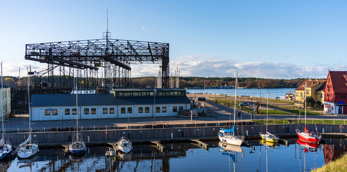 View of the historic shipyard crane and marina with sailboats docked along the waterfront in Klaipeda Klaipeda County Lithuania. View of the historic shipyard crane and marina with sailboats docked along the waterfront in Klaipeda Klaipeda County Lithuania.