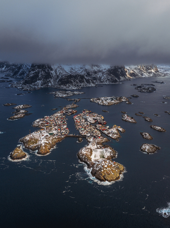 Aerial view of winter s embrace on Henningsv&aelig;r s islands where snow dusted rooftops meet the moody blues of the Norwegian Sea Henningsv&aelig;r Nordland Norway.