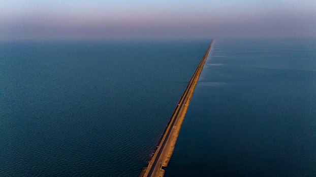 Aerial view of the Road to Heaven a long straight road stretching through the calm waters of the Rann of Kutch under a soft twilight sky in Bhuj Gujarat India. Aerial view of the Road to Heaven a long straight road stretching through the calm waters of the Rann of Kutch under a soft twilight sky in Bhuj Gujarat India.