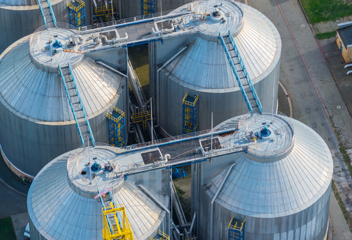 Aerial view of industrial waste water treatment plant with large metal storage tanks connecting walkways and piping infrastructure in Poland. Aerial view of industrial waste water treatment plant with large metal storage tanks connecting walkways and piping infrastructure in Poland.